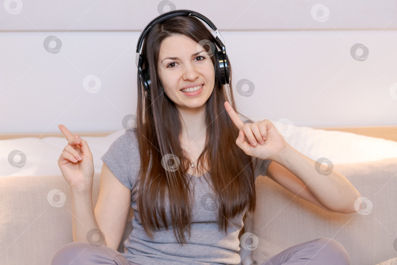 Скачать Женщина в наушниках указывает на что-то фотосток Ozero