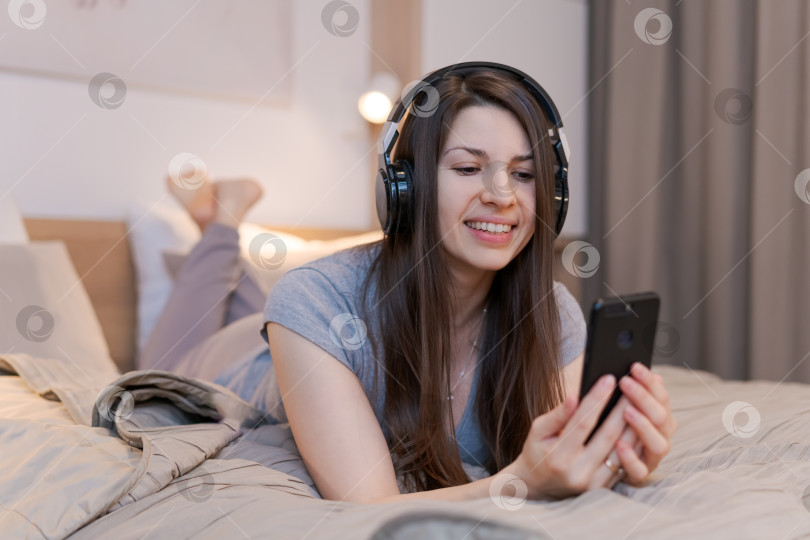 Скачать Женщина лежит на кровати и разговаривает по мобильному телефону фотосток Ozero