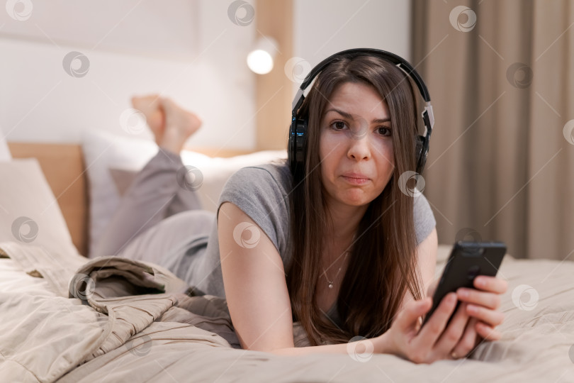 Скачать Женщина лежит на кровати с телефоном в руке фотосток Ozero