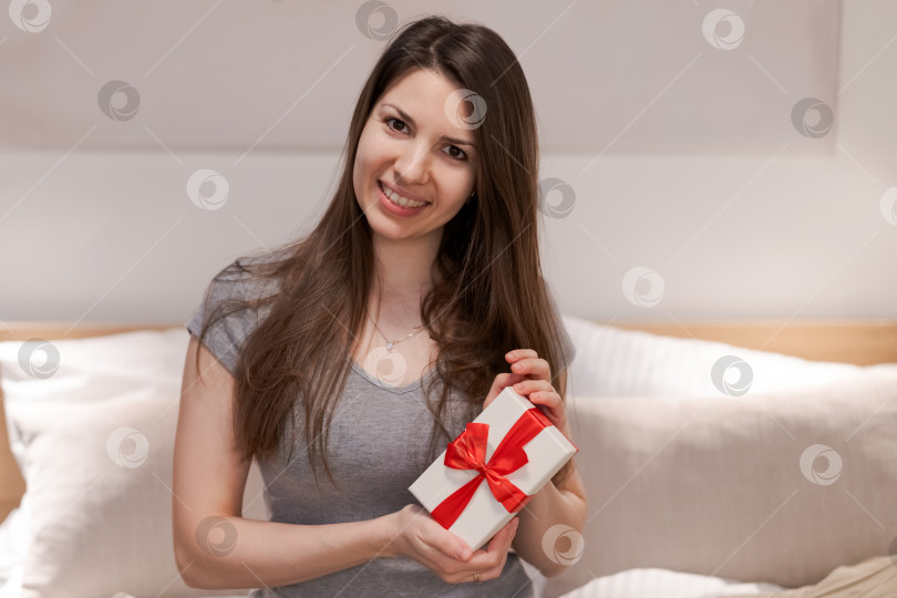 Скачать Женщина держит в руках белую подарочную коробку с красным бантом фотосток Ozero