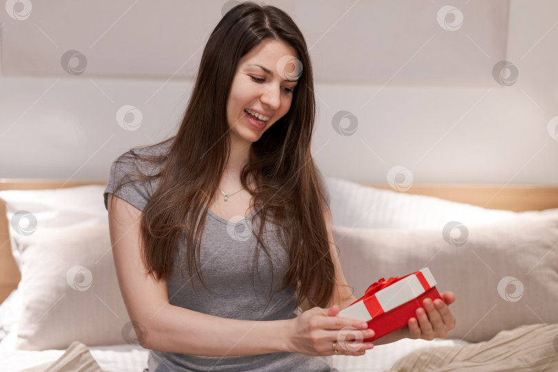 Скачать Женщина держит в руках красную коробку и улыбается фотосток Ozero