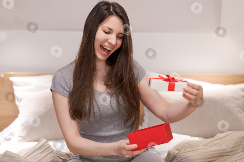 Скачать Женщина сидит на кровати и открывает красную коробку фотосток Ozero