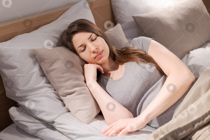 Скачать Женщина спит на кровати, укрывшись подушкой и одеялом фотосток Ozero
