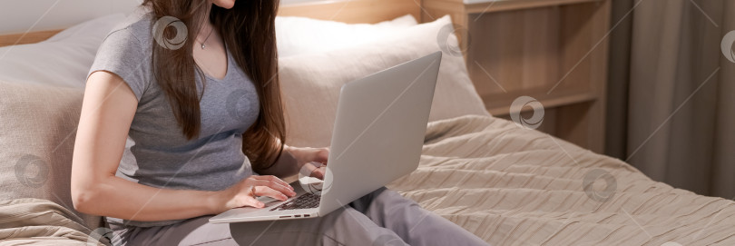 Скачать На кровати сидит женщина, перед ней ноутбук фотосток Ozero