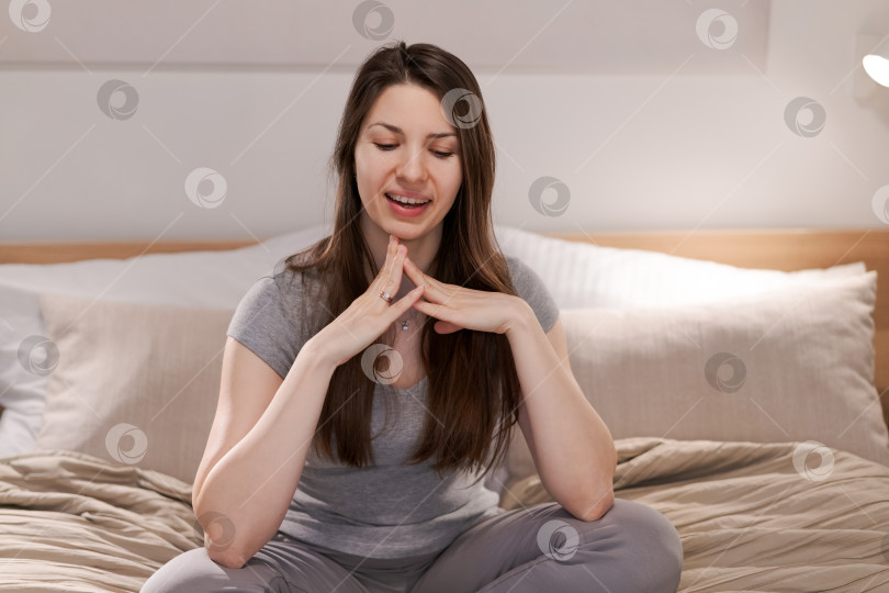 Скачать Женщина сидит на кровати и делает руками знак мира фотосток Ozero