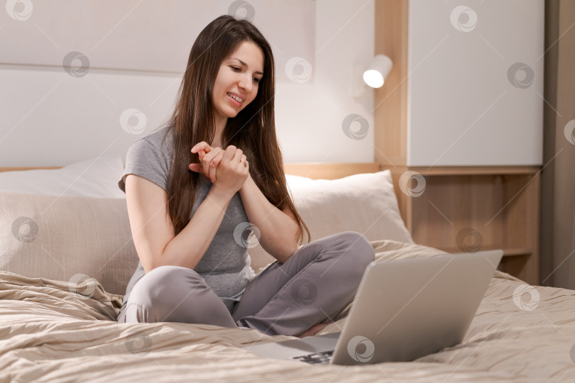 Скачать На кровати сидит женщина, перед ней ноутбук фотосток Ozero