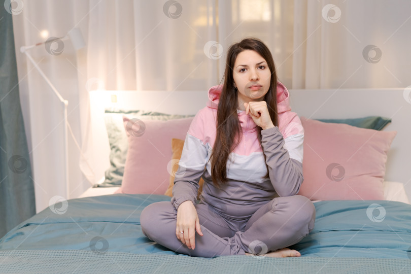 Скачать Женщина сидит на кровати и смотрит в камеру фотосток Ozero