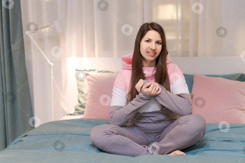 Скачать Женщина сидит на кровати в комнате с розовыми и голубыми подушками фотосток Ozero