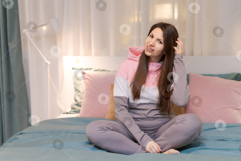 Скачать Женщина сидит на кровати, обхватив голову руками фотосток Ozero