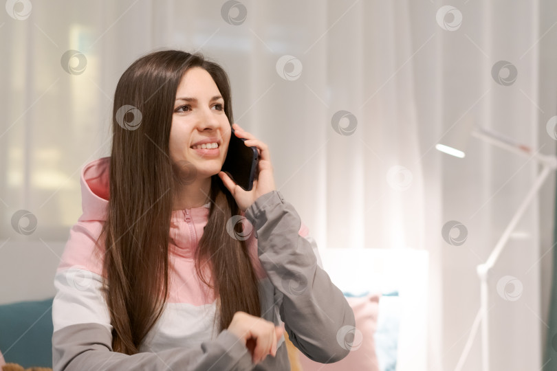 Скачать Женщина разговаривает по мобильному телефону, сидя на диване фотосток Ozero