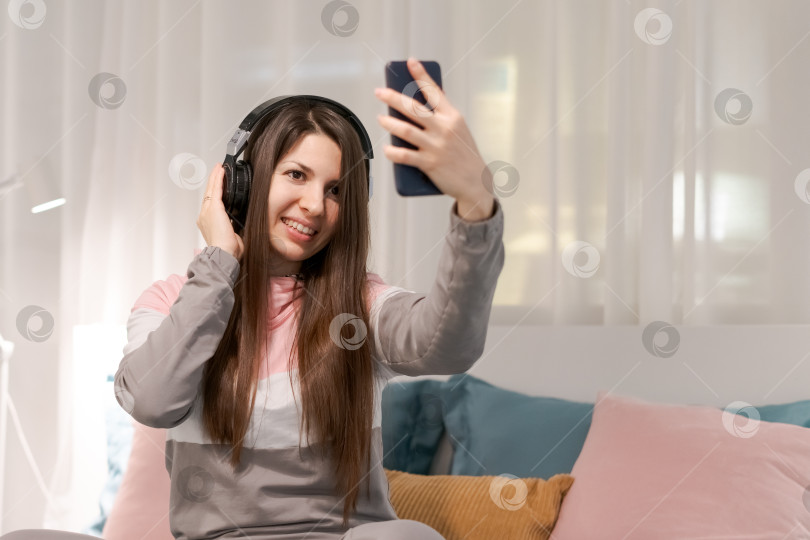 Скачать Женщина делает селфи в наушниках и улыбается фотосток Ozero
