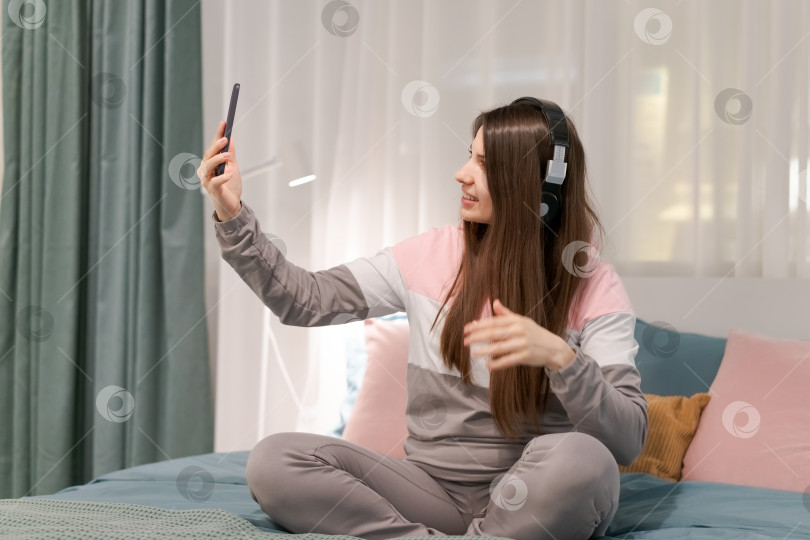 Скачать Женщина сидит на кровати и делает селфи на свой мобильный телефон фотосток Ozero