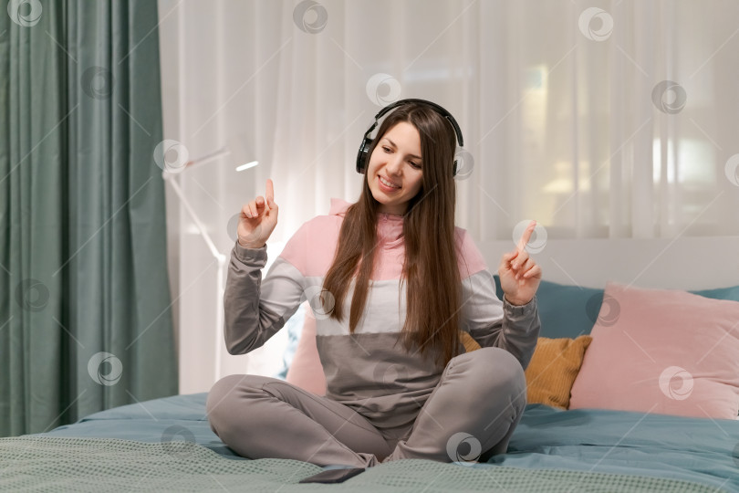 Скачать Женщина сидит на кровати и указывает на что-то пальцем фотосток Ozero