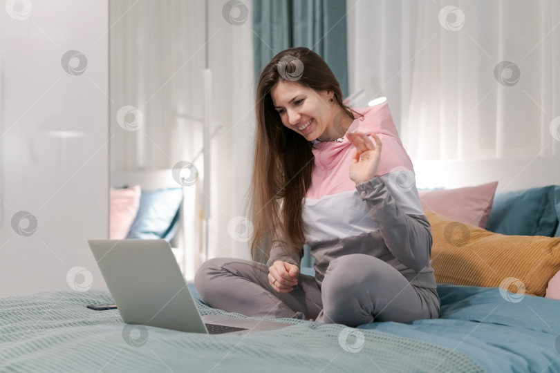 Скачать На кровати сидит женщина, перед ней ноутбук фотосток Ozero