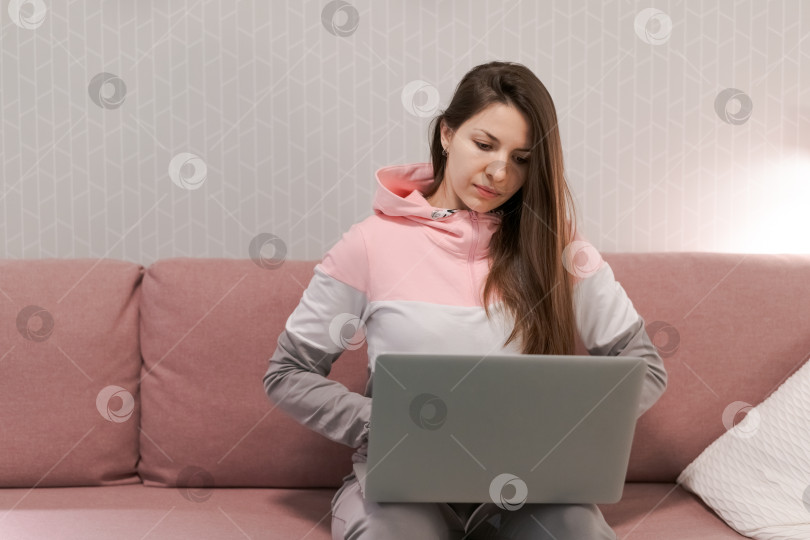 Скачать Женщина сидит на диване с ноутбуком перед собой фотосток Ozero