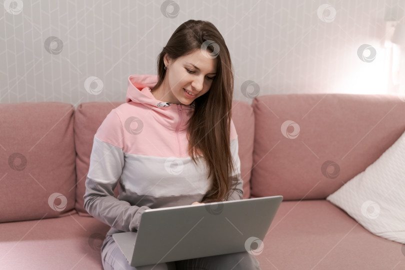 Скачать Женщина сидит на диване с ноутбуком перед собой фотосток Ozero