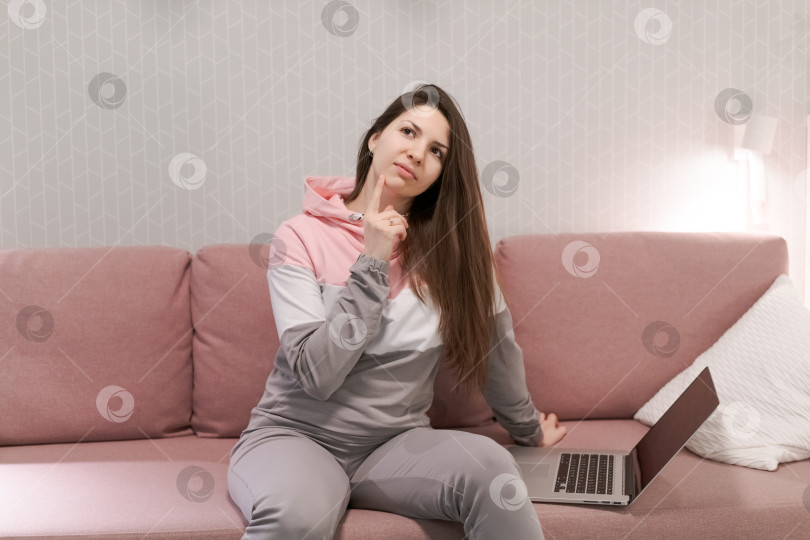 Скачать Женщина сидит на диване с открытым ноутбуком перед собой фотосток Ozero