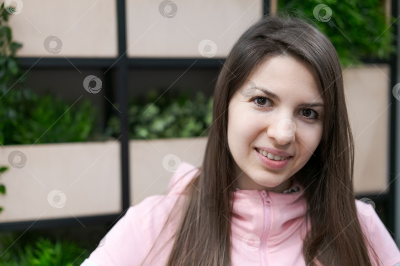 Скачать Женщина с длинными каштановыми волосами одета в розовую куртку и улыбается фотосток Ozero