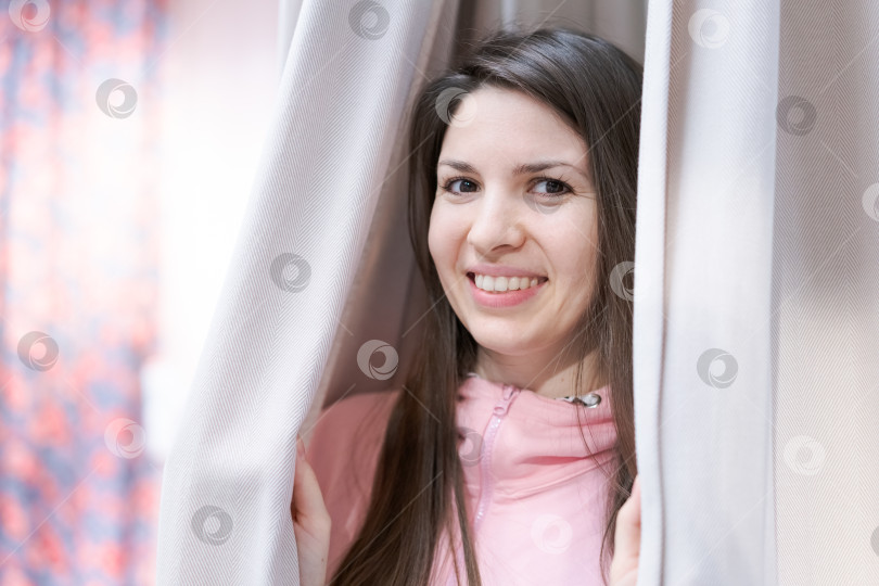 Скачать Женщина улыбается, стоя за занавеской фотосток Ozero