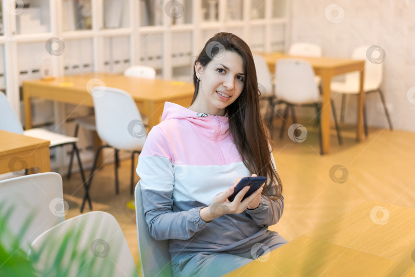 Скачать За столом сидит женщина с мобильным телефоном в руке фотосток Ozero