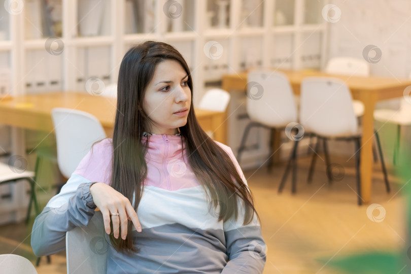 Скачать Женщина сидит в кресле в комнате, где много стульев и столов фотосток Ozero