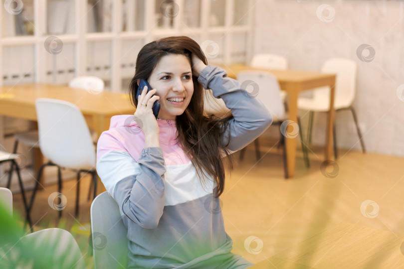 Скачать Женщина разговаривает по мобильному телефону в комнате со стульями и столами фотосток Ozero