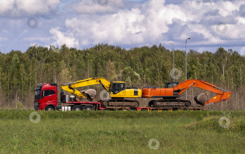 Скачать Автомобильный прицеп с двумя гусеничными экскаваторами на длинной платформе. Перевозка тяжелой строительной техники. Россия. 08.2025 фотосток Ozero