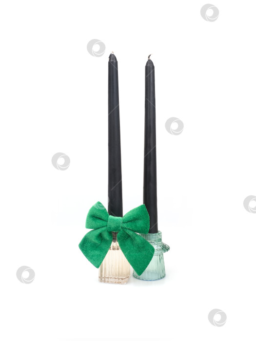 Скачать Черные свечи с зеленым бархатным бантом в стеклянных подсвечниках, выделяющиеся на белом фоне, уже готовы к изготовлению. Чрезвычайно высокое разрешение фотосток Ozero