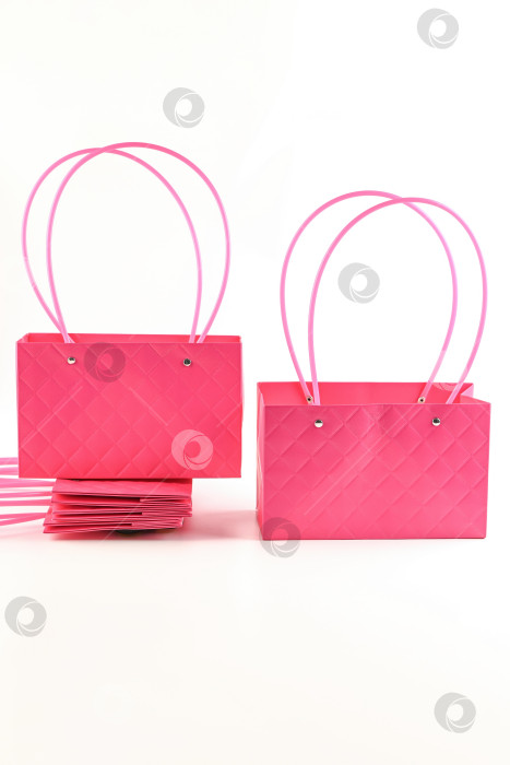 Скачать Пластиковые подарочные пакеты для цветов цвета фуксии с длинными ручками-петлями на белом фоне прямоугольной формы идеально подходят для упаковки букетов, декора и подарков. фотосток Ozero