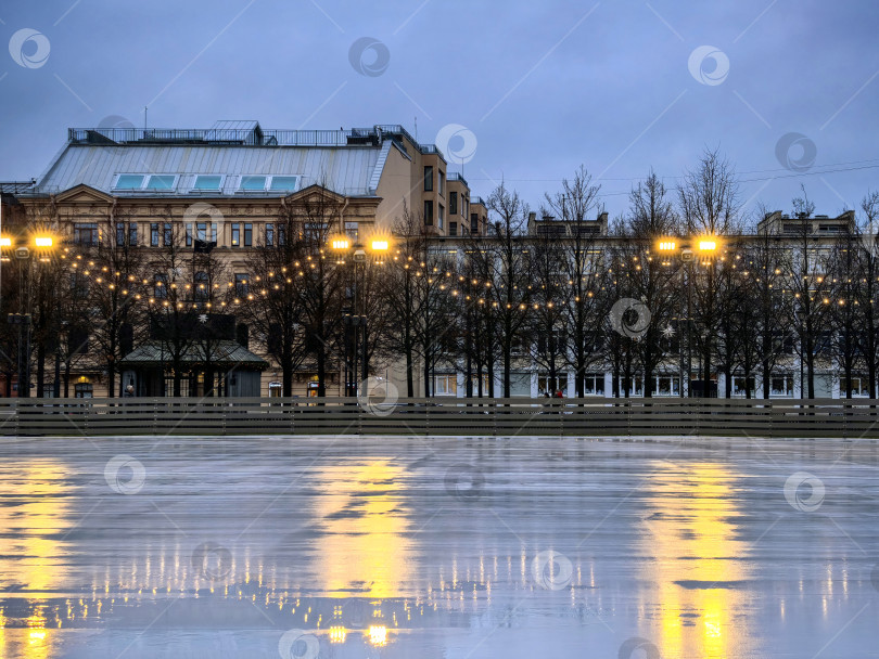 Скачать Санкт-Петербург, Россия - 17 декабря 2025 года. Вечерний вид ледового катка с отражениями и огнями. Снимок сделан на смартфон. фотосток Ozero