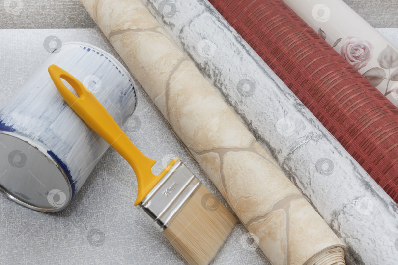 Скачать Разноцветные обои, баллончик с краской и кисть на текстурированном фоне. Место для текста. Концепция ремонта дома или квартиры. Вид сверху фотосток Ozero