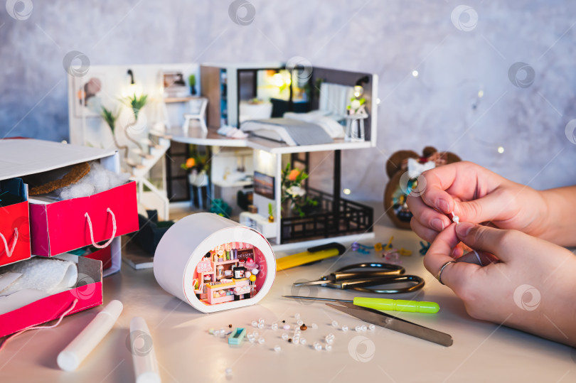 Скачать Детские ручки нанизывают бусинки, чтобы украсить крошечный домик на столе фотосток Ozero