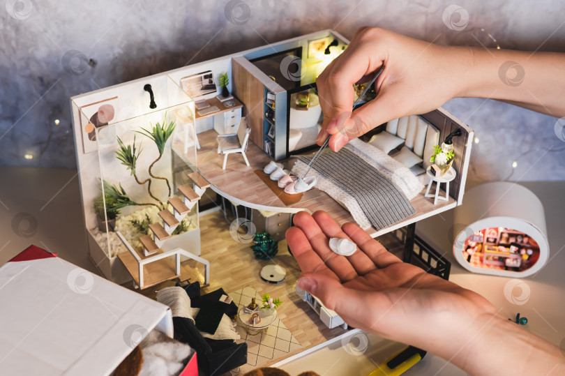 Скачать Детские ручки кладут тапочки рядом с кроватью в крошечную комнатную коробку. фотосток Ozero