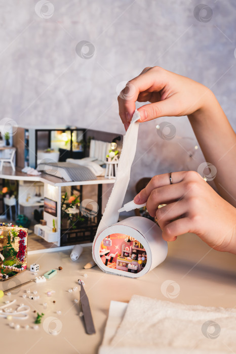 Скачать Рука девушки приклеивает ткань к крошечному ящичку для белья на столе, вид сверху фотосток Ozero