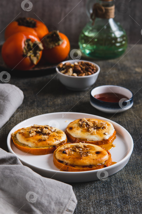 Скачать Вкуснейшая запеченная хурма с творогом, орехами и медом на тарелке в вертикальном положении фотосток Ozero