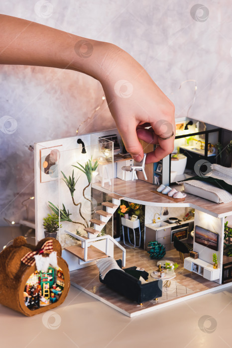 Скачать Детская рука ставит стул на стол на втором этаже крошечного домика на столе фотосток Ozero