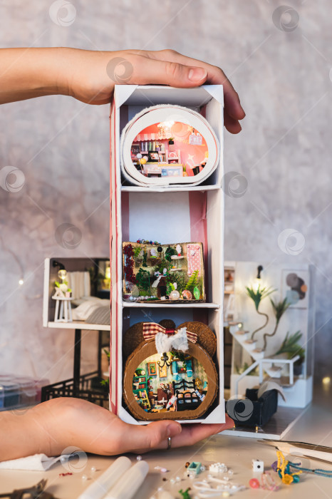 Скачать Три миниатюрных комода на вертикальной подставке в детских руках фотосток Ozero