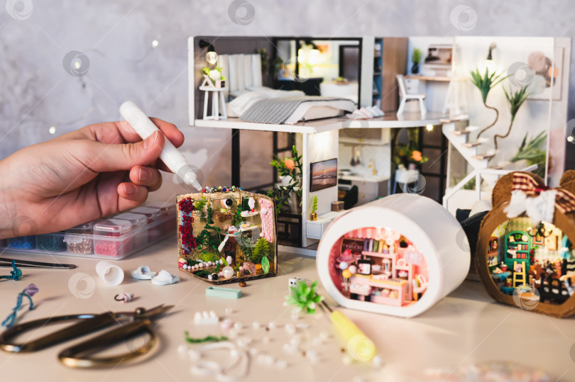 Скачать Девушка приклеивает детали к миниатюрной шкатулке для хранения вещей, стоящей на столе фотосток Ozero