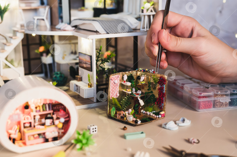 Скачать Детская рука с помощью пинцета кладет бусинку на миниатюрную шкатулку для хранения вещей фотосток Ozero