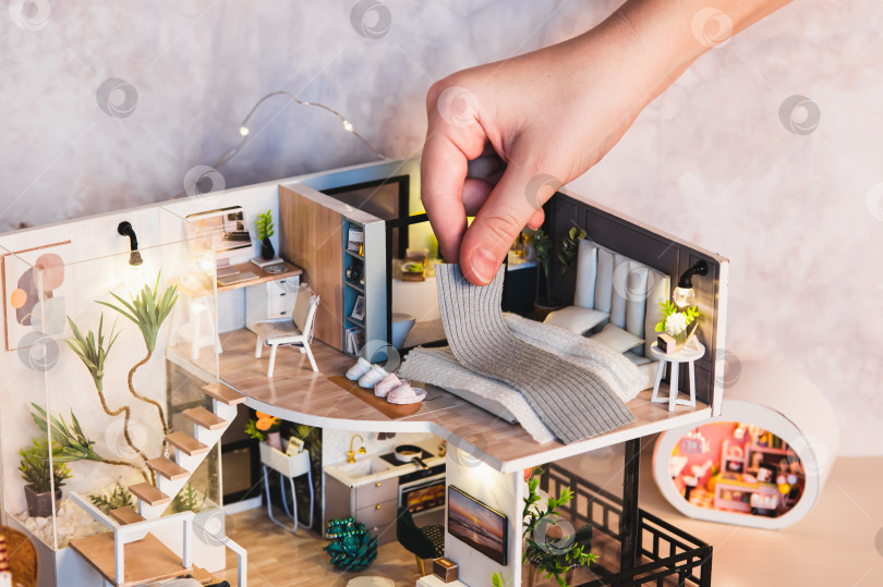 Скачать Детская рука расстилает одеяло на кровати на втором этаже крошечного домика, на столе фотосток Ozero