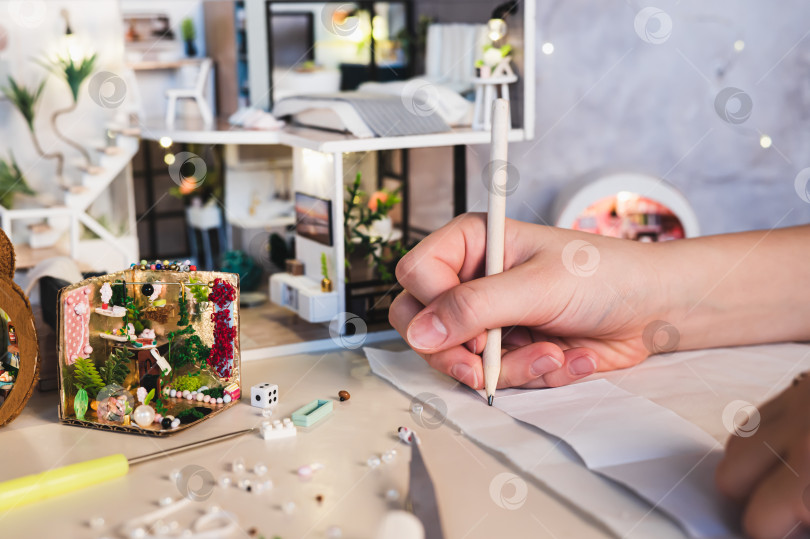 Скачать Детская рука карандашом рисует линию на ткани для кукольного домика. фотосток Ozero