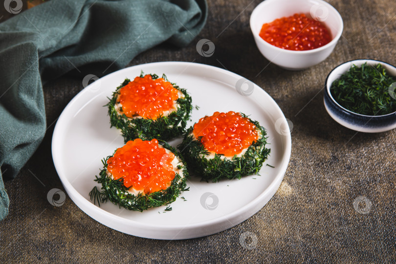 Скачать Креативные мини-бутерброды с красной икрой, сливочным маслом и укропом на тарелке на столе фотосток Ozero