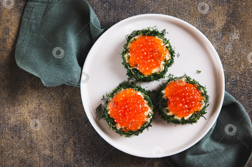 Скачать Крупный план оригинальных маленьких бутербродов с маслом и красной икрой на тарелке на столе вид сверху фотосток Ozero
