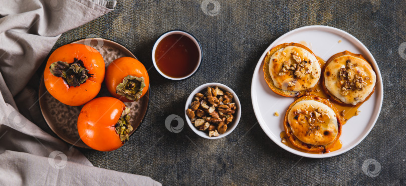 Скачать Запеченная хурма со сливочным сыром и орехами на тарелке, установленной на столешнице в вертикальном положении фотосток Ozero