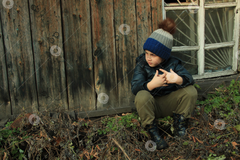 Скачать Одинокий ребенок сидит рядом с разбитым окном. фотосток Ozero