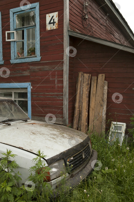 Скачать Атмосферная сцена со старым деревянным домом и брошенной машиной в русской деревне фотосток Ozero