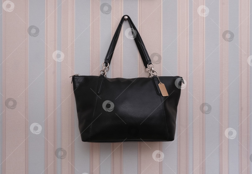 Скачать Элегантная черная сумка с золотым замком, выделяющимся на полосатом фоне фотосток Ozero