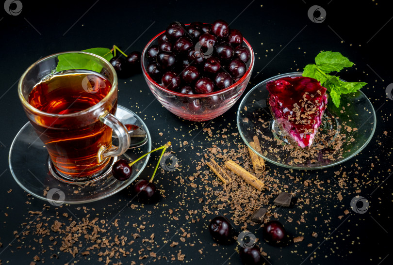 Скачать натюрморт с чашкой крепкого чая, спелой вишней и вишневым тортом на черном фоне фотосток Ozero