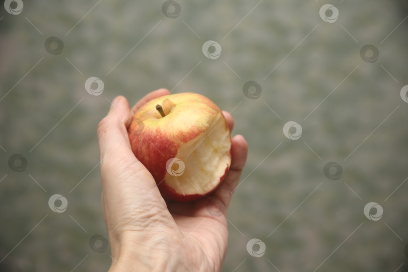 Скачать Женщина держит красно-жёлтое яблоко фотосток Ozero