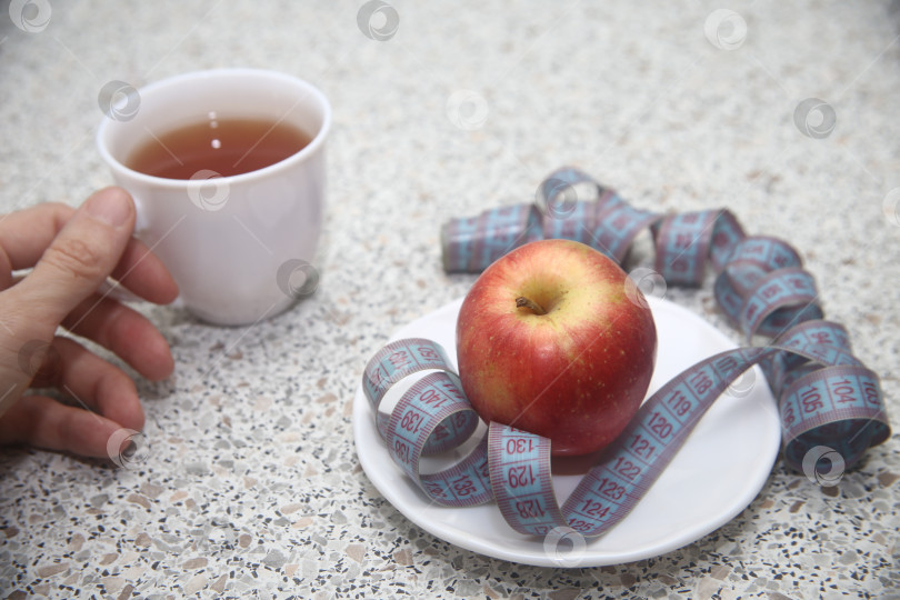 Скачать Яблоко красное в тарелке и сантиметровая лента фотосток Ozero
